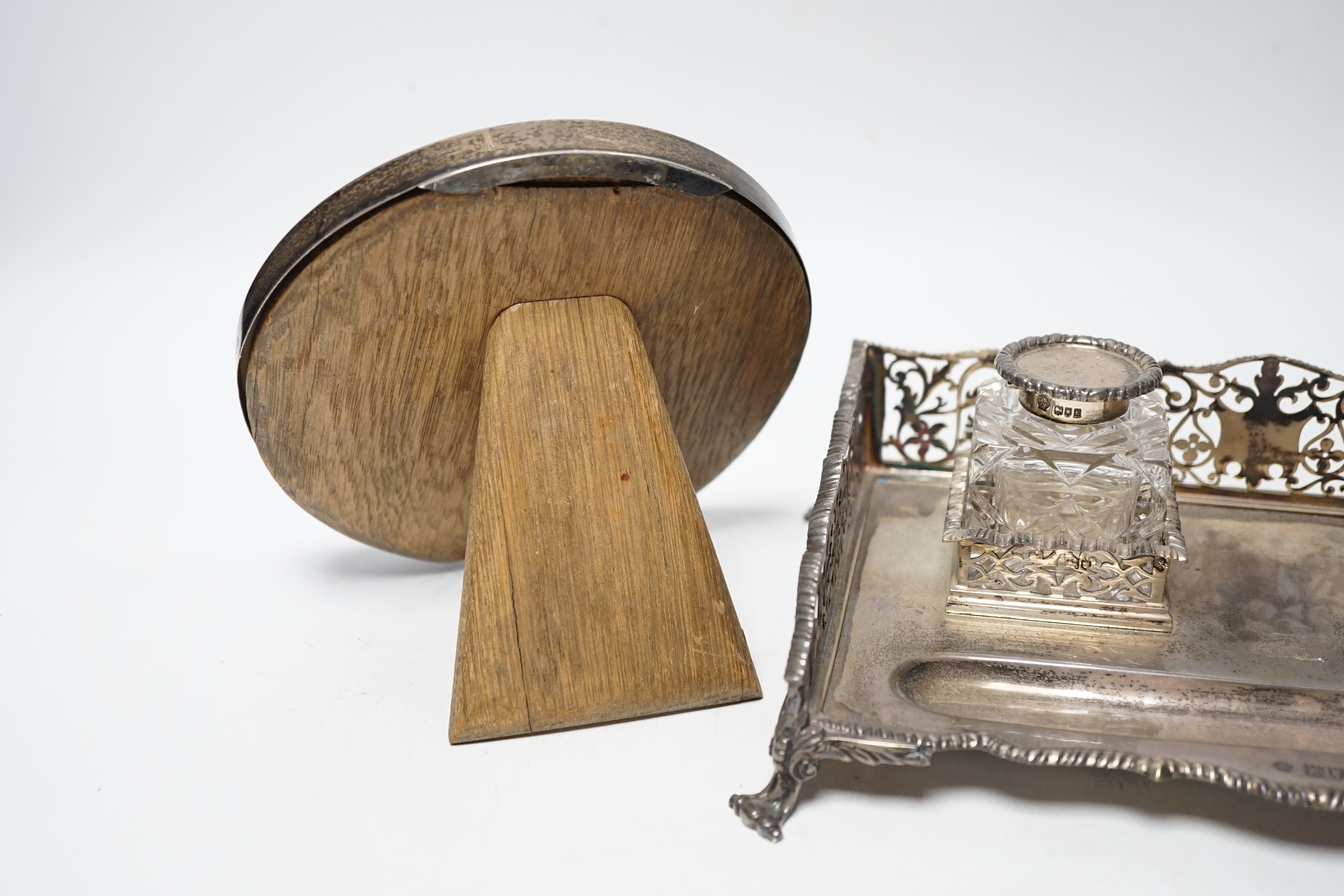 An Edwardian silver rectangular inkstand with pierced three quarter gallery and two mounted cut glass wells, William Hutton & Sons Ltd, London, 1905, 22.3cm and a George V silver mounted circular photograph frame.